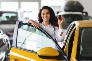 Woman driving their new financed car out of a car sales yard